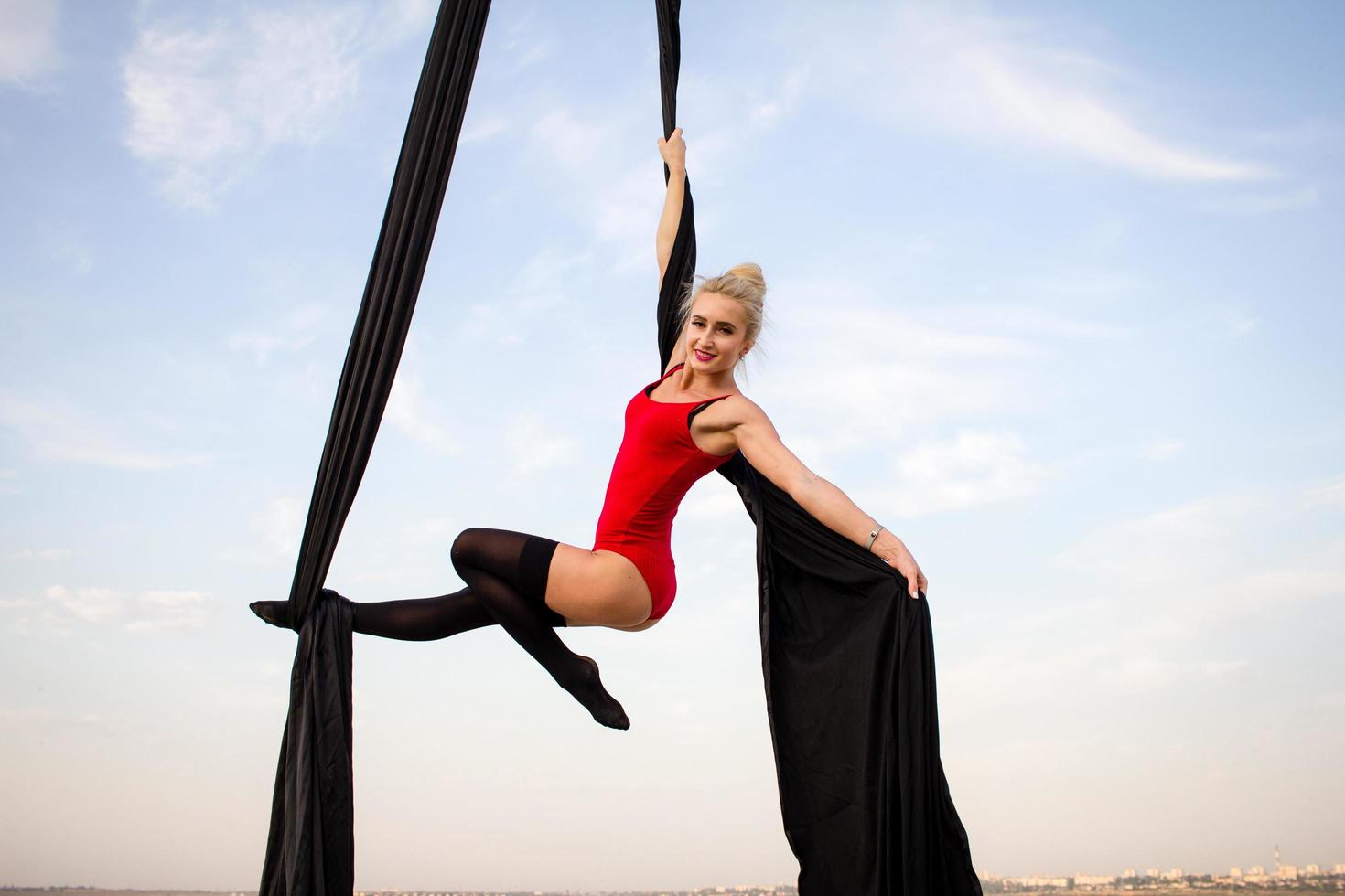 exercises with aerial silk outdoor, sky background. beautiful fit woman training acrobatic in airt. photo