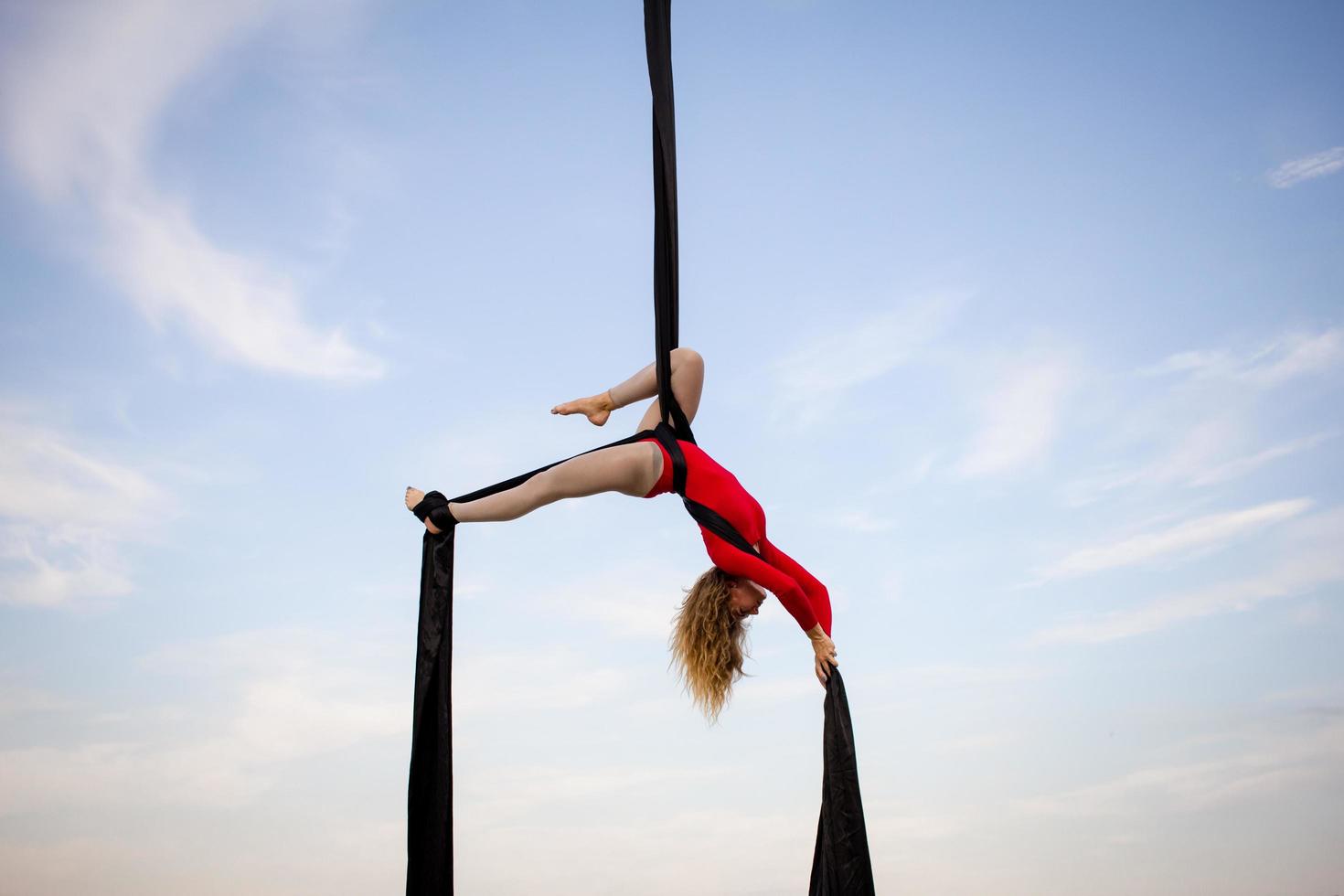 exercises with aerial silk outdoor, sky background. beautiful fit woman training acrobatic in airt. photo