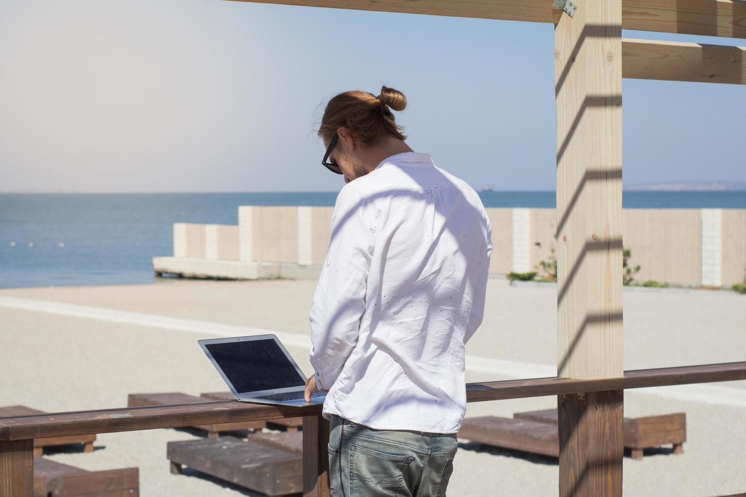 young men with laptopp working near the pool, freelancer in hotel on vacation with notebook photo