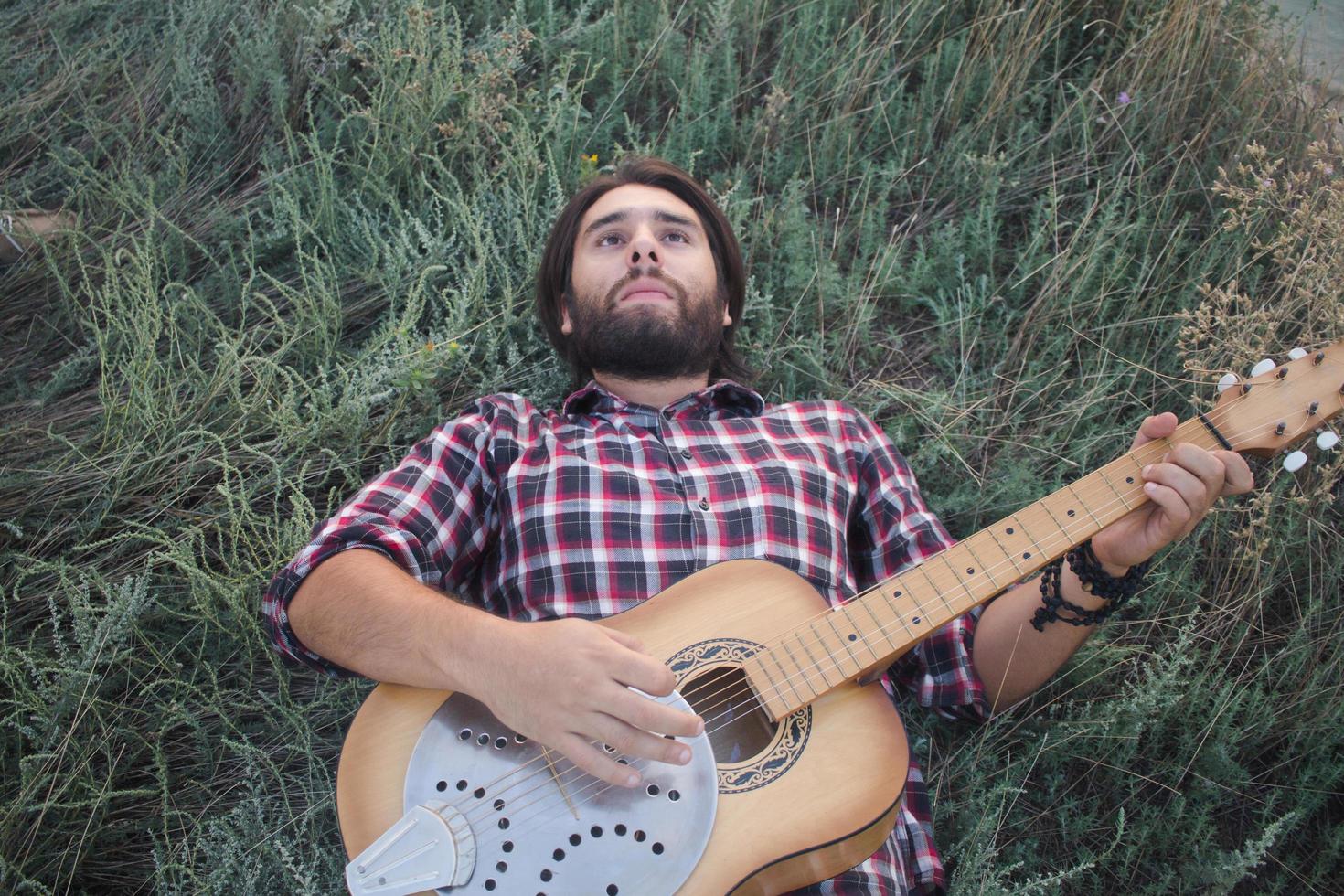 Young male with acoustic guitar outdoors photo