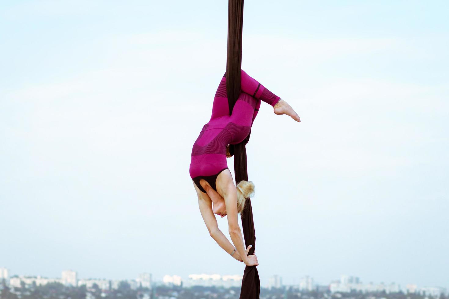 exercises with aerial silk outdoor, sky background. beautiful fit woman training acrobatic in airt. photo