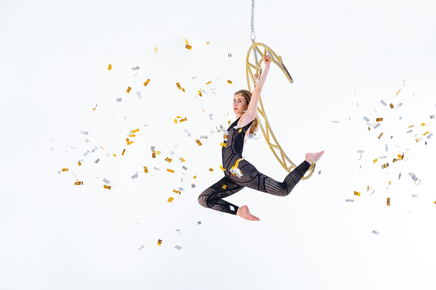 Woman hanging in aerial silk in white studio photo