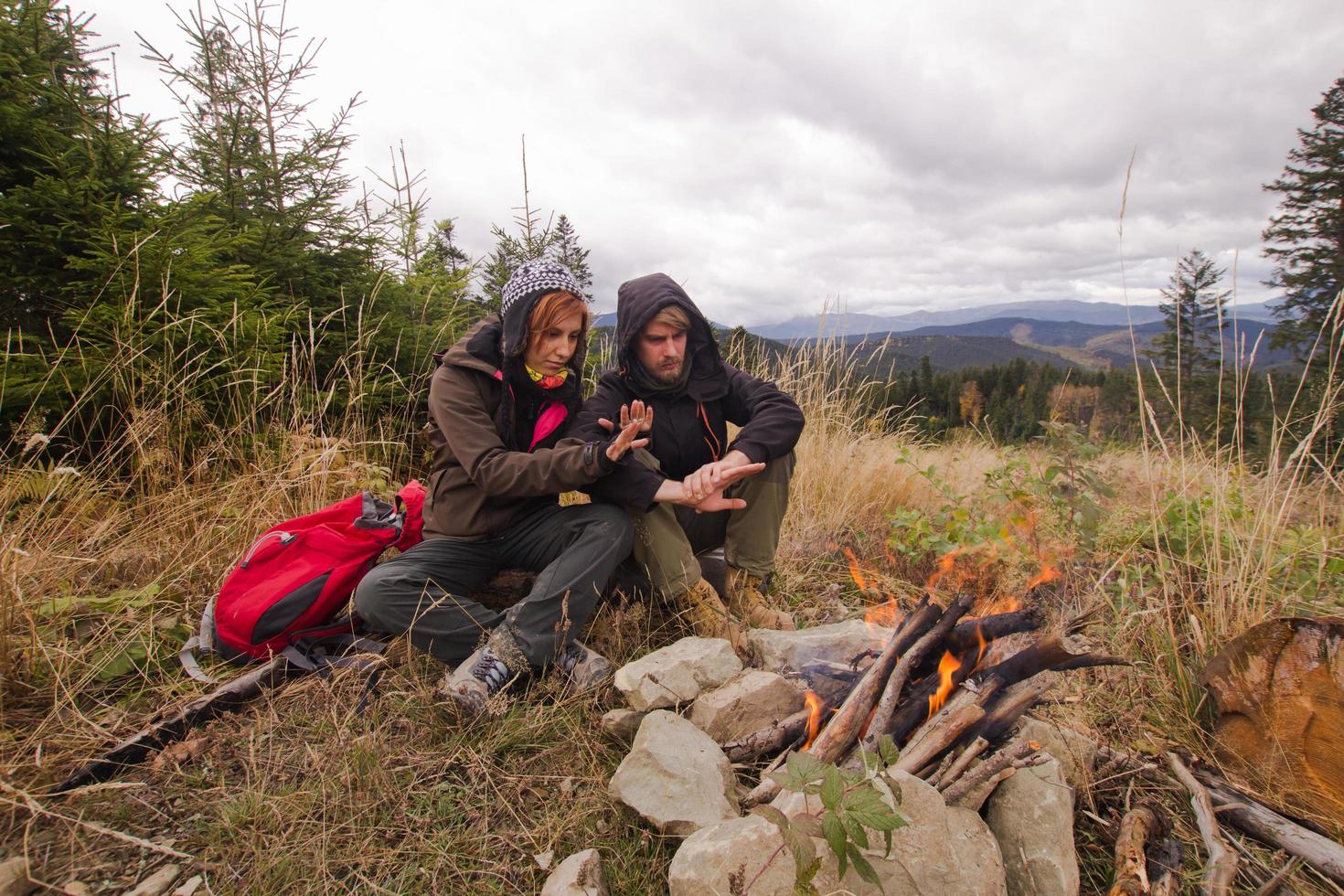 pareja joven excursionistas con tazas termos en el bosque, viajeros en mauntains bebiendo té o café foto