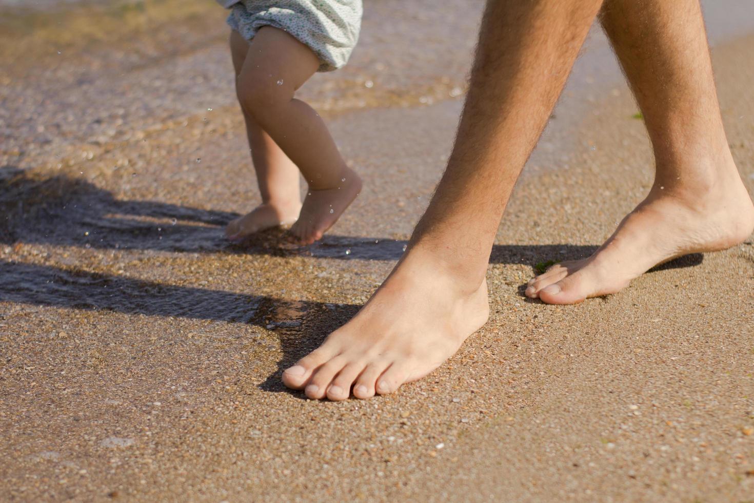 Cerrar foto de padre con un niño de un año caminando por la playa en verano