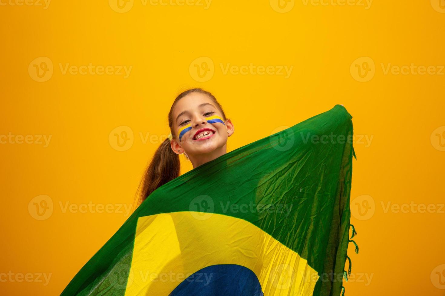 Football supporter, Brazil team. World Cup. Beautiful little girl cheering for her team on yellow background photo