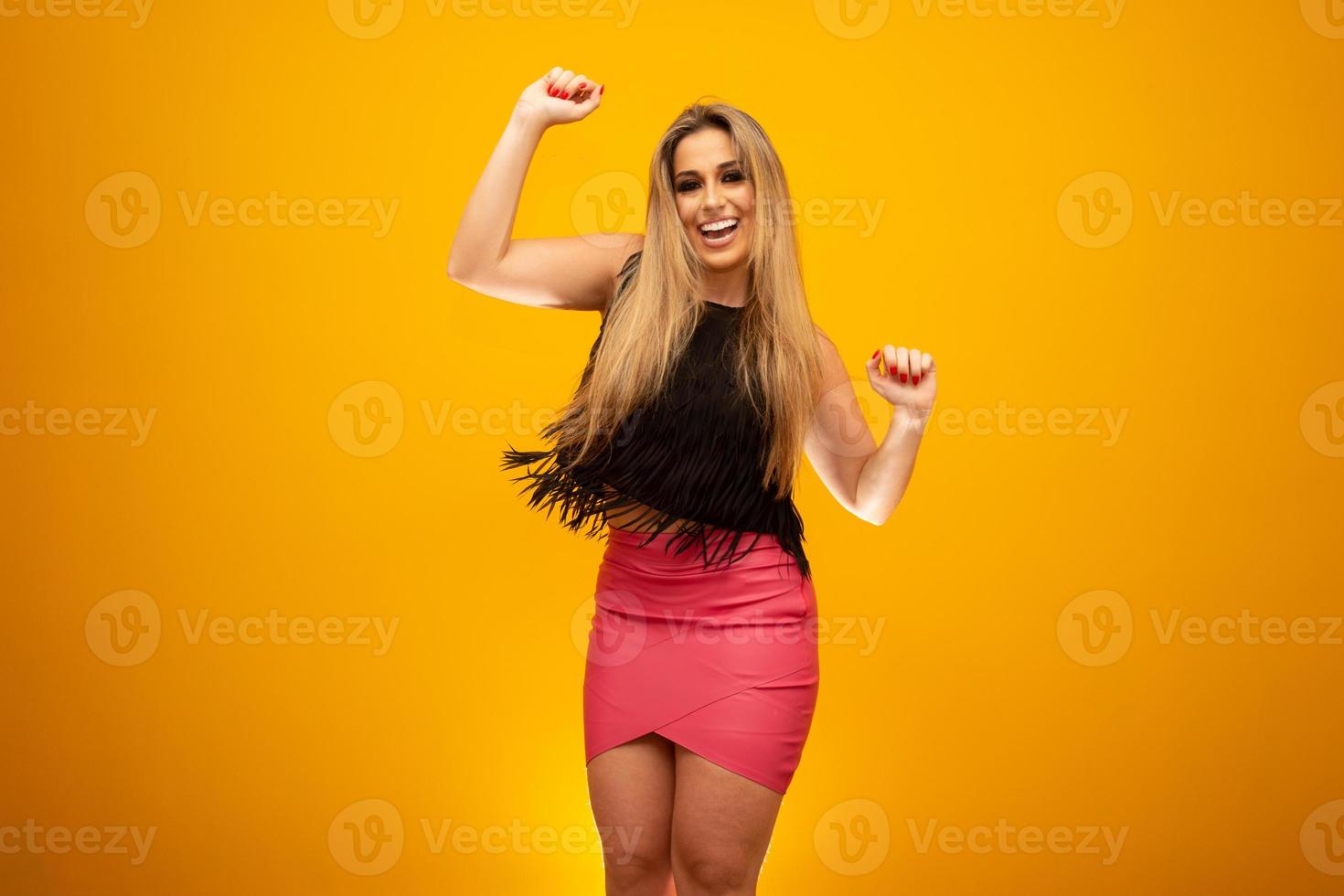 Beautiful blonde woman in fashion theme. Young beautiful woman wearing fashion t-shirt standing over yellow background with smile on face, natural expression. Laughing confident. photo