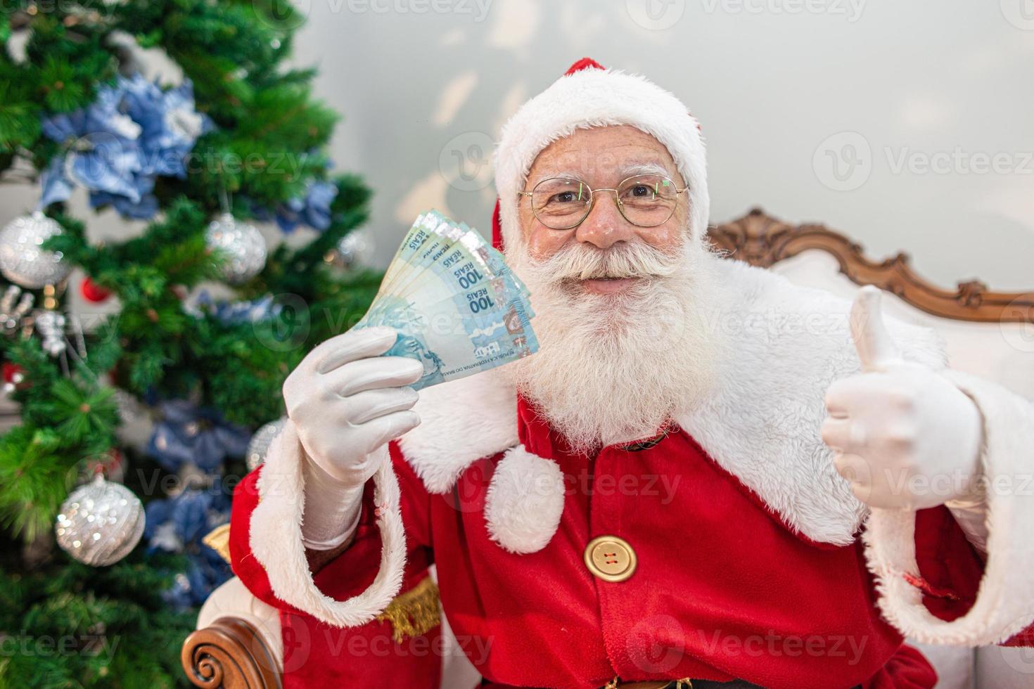 santa claus contando billetes de dinero brasileño. notas reales billetes de 100 reales. concepto de ahorro para fin de año. gastar en navidad. gastado en regalos de navidad. foto