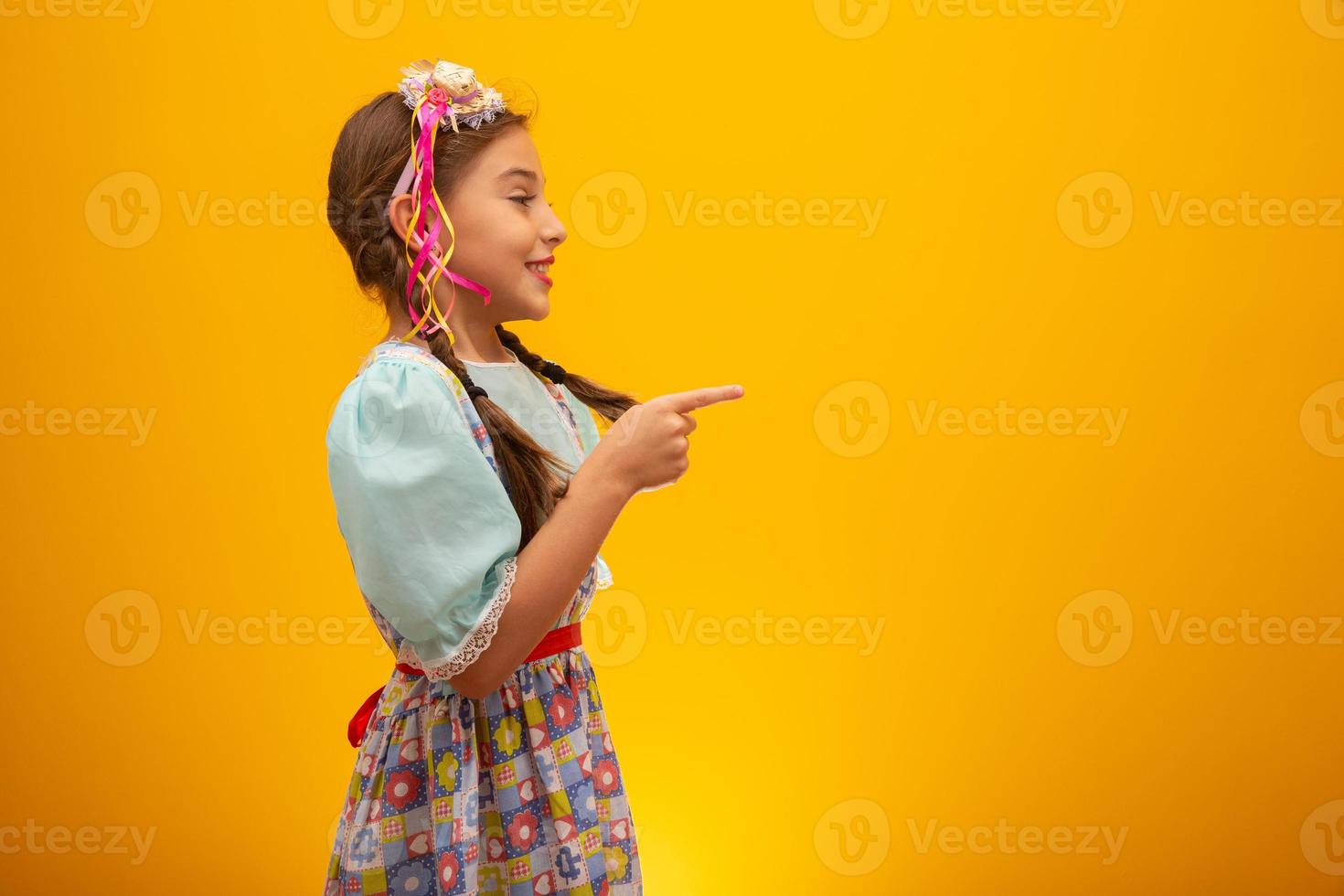 Child in typical clothes of famous Brazilian party called Festa Junina in celebration of Sao Joao. Beautiful girl on yellow background. photo