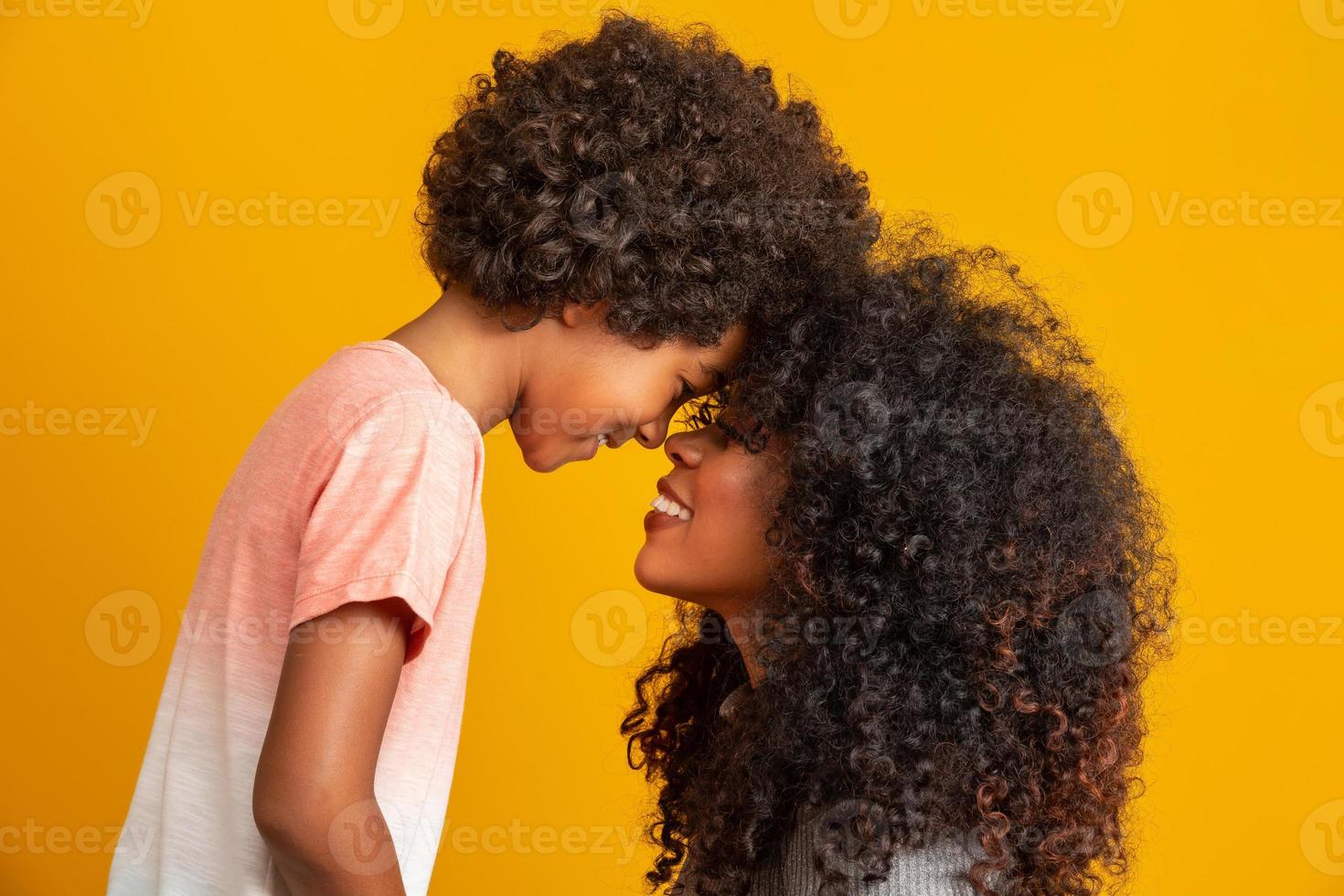 retrato de una joven madre afroamericana con un hijo pequeño. fondo amarillo familia brasileña. foto