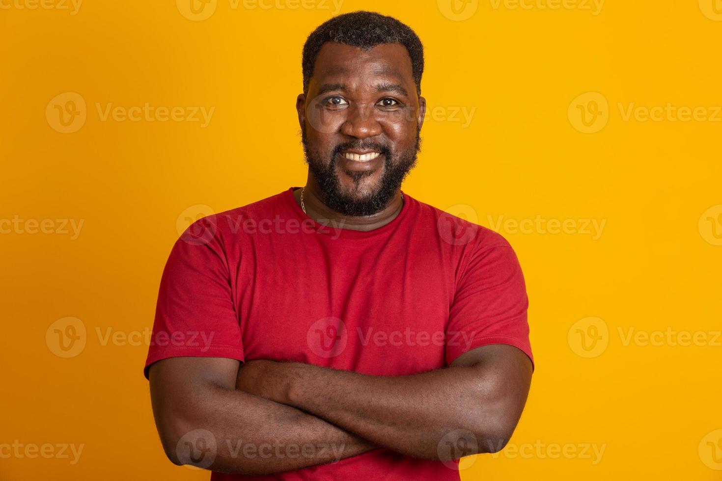 Positive dark skinned male has joyful expression and broad smile with white teeth, being in good mood. African American man smile happy face. Crossed arms. photo