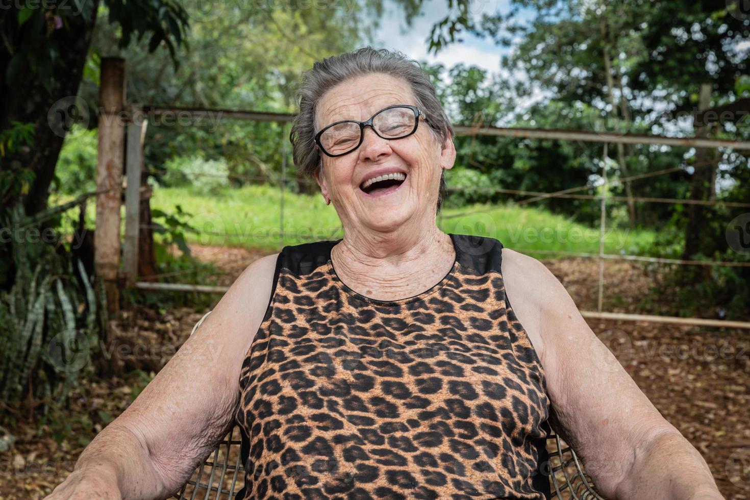 anciana granjera feliz con anteojos sonriendo y mirando a la cámara foto