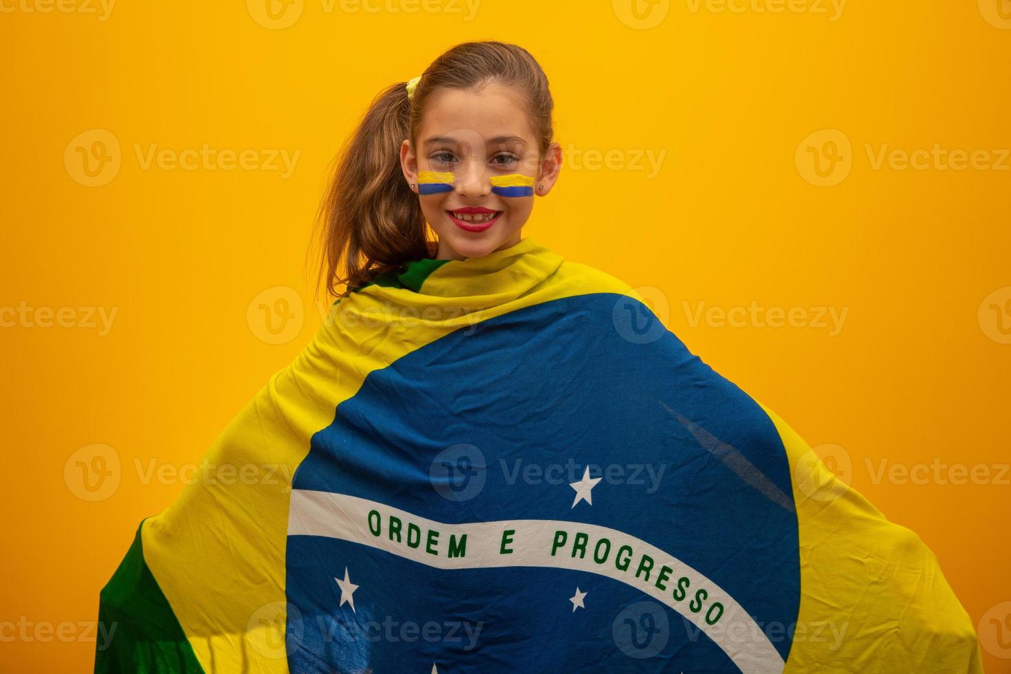 Football supporter, Brazil team. World Cup. Beautiful little girl cheering for her team on yellow background photo