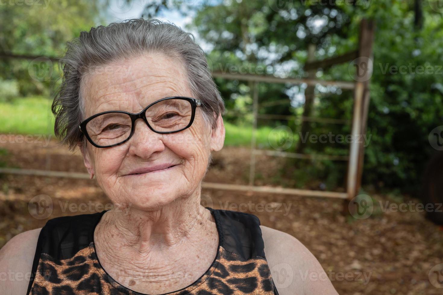 Senior happy old farmer woman with eyeglasses smiling and looking at camera photo