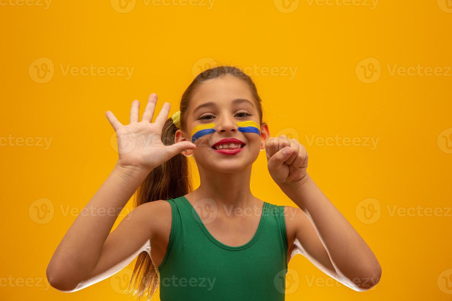 Football supporter, Brazil team. World Cup. Beautiful little girl cheering for her team on yellow background photo