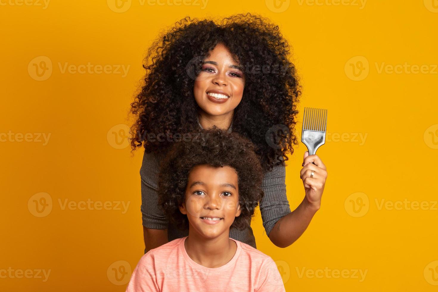 jóvenes afroamericanos peinándose aislados. tenedor para peinar el cabello rizado. fondo amarillo foto