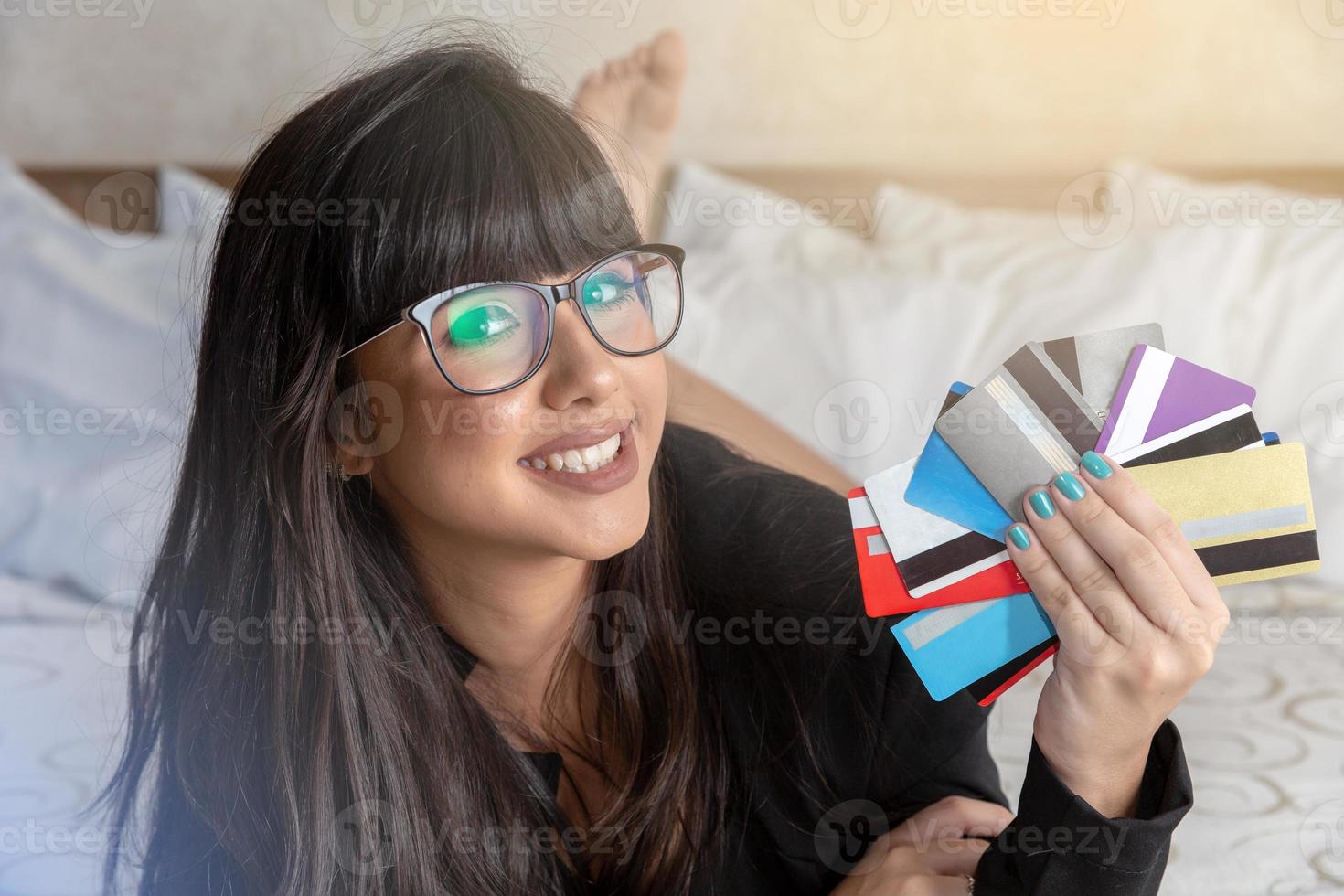 Beautiful woman holding a hand multiple credit cards on the bed. Plastic money, electronic money and digital money will change the global marketing in the near future. Concept of rich woman. photo