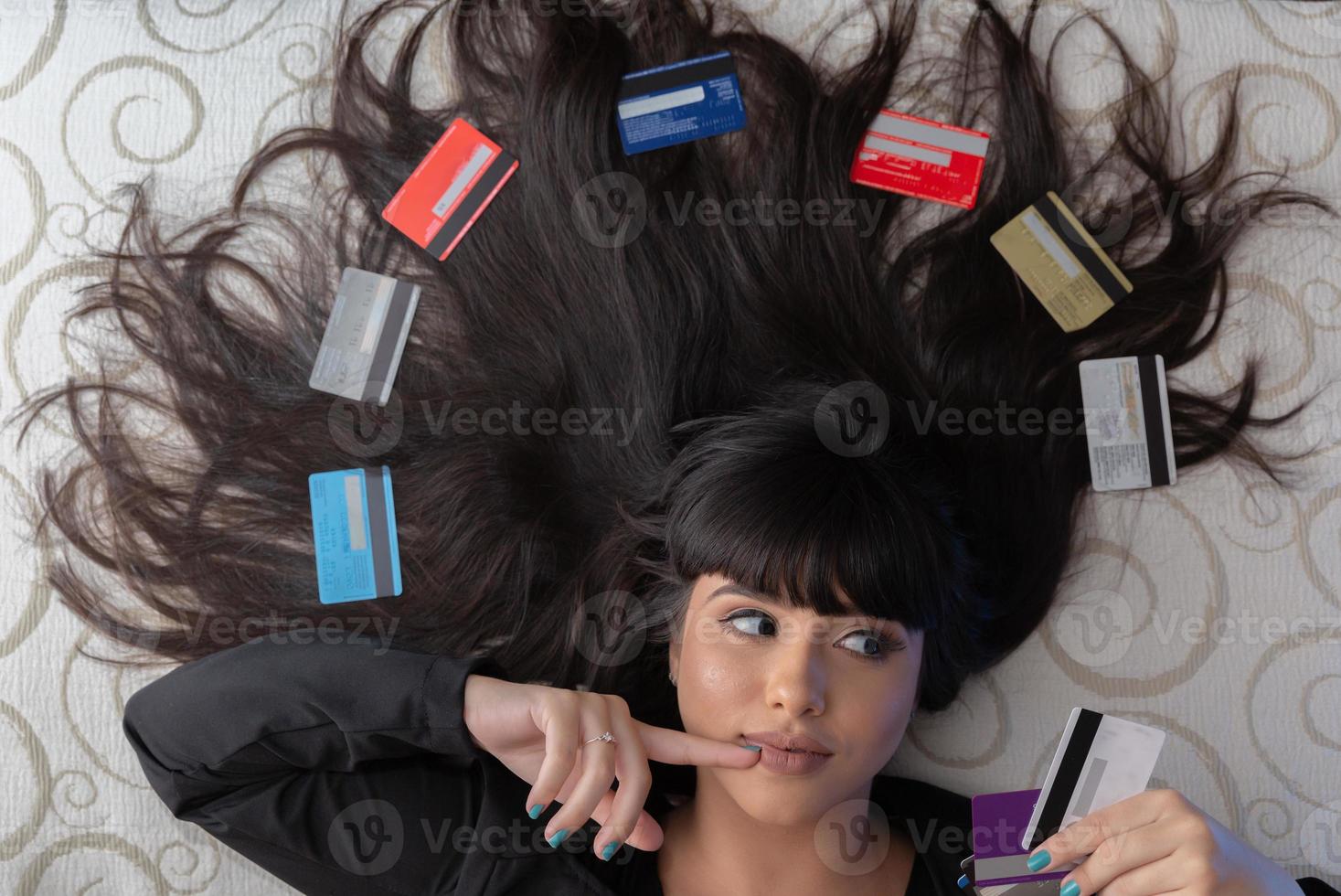 Beautiful woman with multiple credit cards on the bed. Plastic money, electronic money and digital money will change the global marketing in the near future. Concept of rich woman. photo