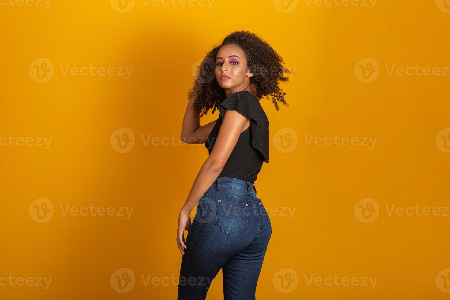 joven mujer negra en su espalda con peinado afro sobre fondo amarillo. chica con peinado africano. foto de estudio