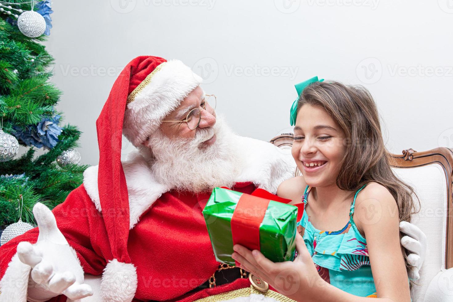 Santa Claus delivering a gift box to a little girl. Christmas eve, delivery of gifts. photo