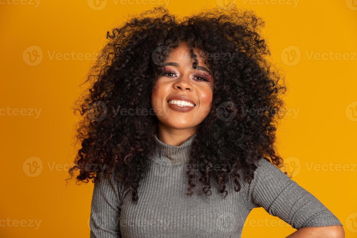 retrato de belleza de mujer afroamericana con peinado afro y maquillaje glamuroso. mujer brasileña. raza mixta. Pelo RIZADO. peinado fondo amarillo foto