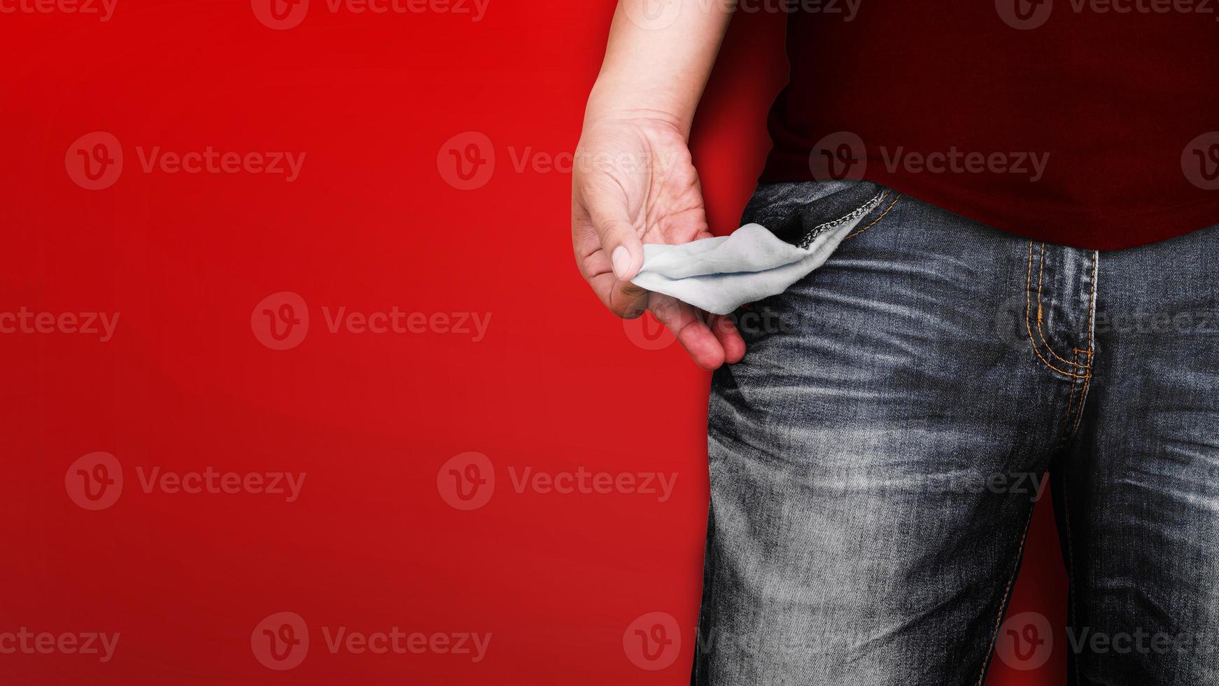Man showing his empty pocket on red wall background. photo