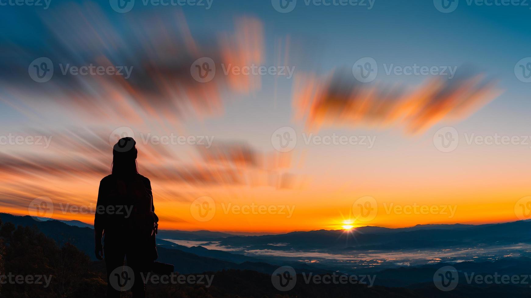 vista trasera del joven fotógrafo hipster sosteniendo la cámara con puesta de sol en el fondo natural de la montaña. foto