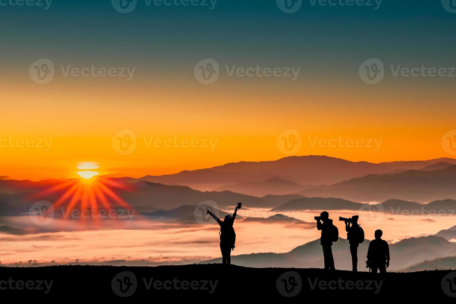 Silhouette image of traveler men and women taking photos with sunrise in the morning on mountains natural background.