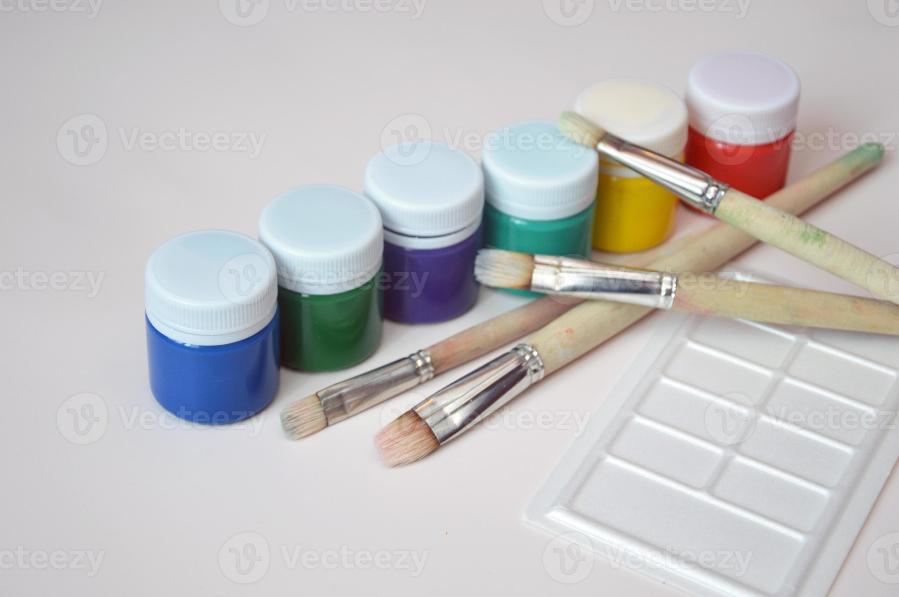 Palette with samples of multi-colored gouache paints and brushes after  painting. Close-up on a white background. Free space for text. 7731836  Stock Photo at Vecteezy