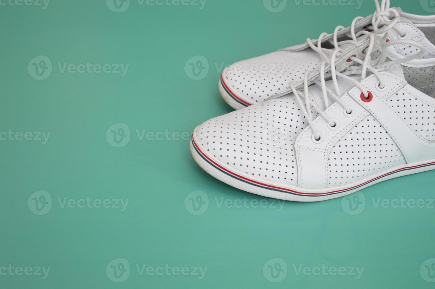 White sports shoes, gumshoes on a mint green background. View from above. Free space for text. Modern shoes for sports, walking, running. photo
