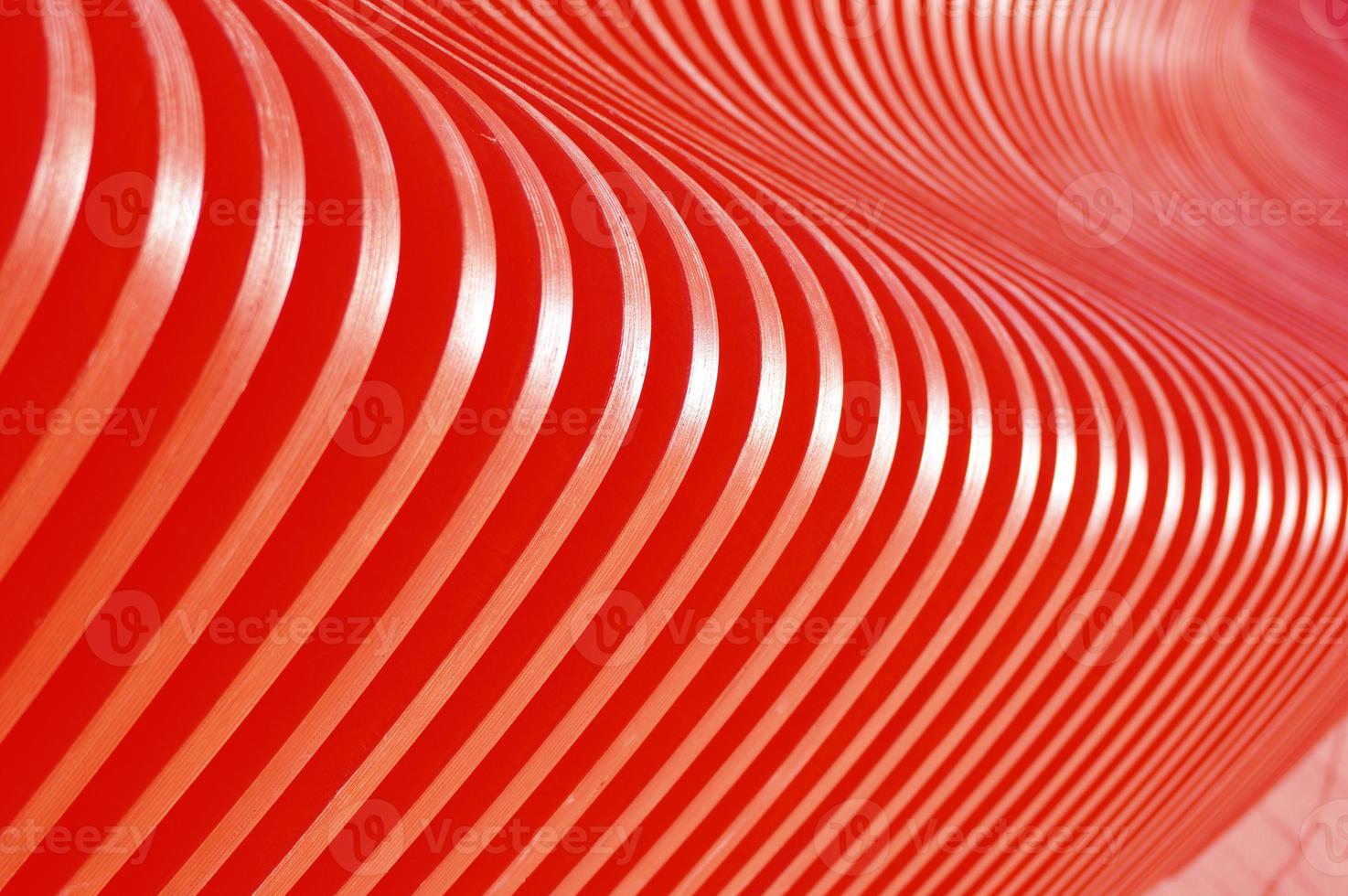 Wooden curved red slats. Abstract background. Glare of the sun on the surface. Building facade element. photo