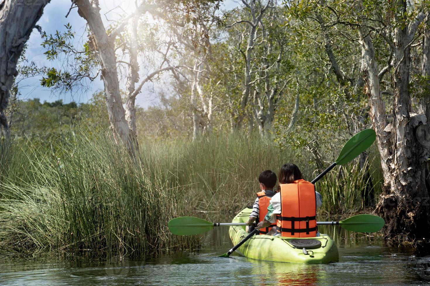 madre e hijo con chalecos salvavidas y bastones de kayak. viajar en humedales en bosques de manglares. en el centro de la planta del este provincial de rayong de rayong tailandia. foto