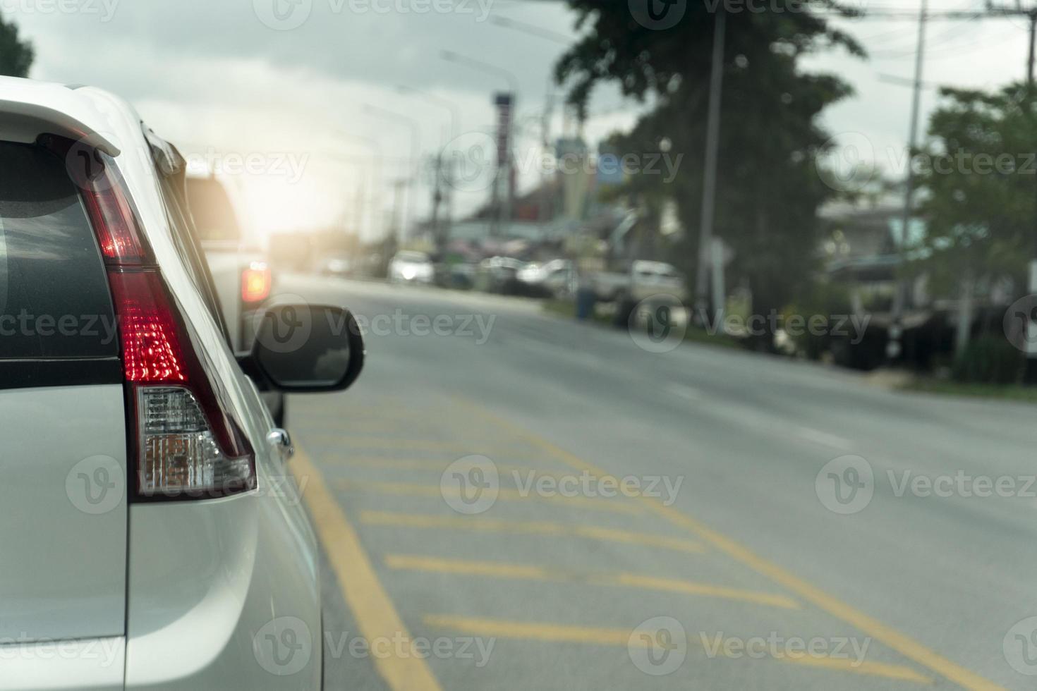 Rear side of white car stop on tha asphalt road. Turn on light brake and queue from traffic light control in the countryside of Thailand. photo