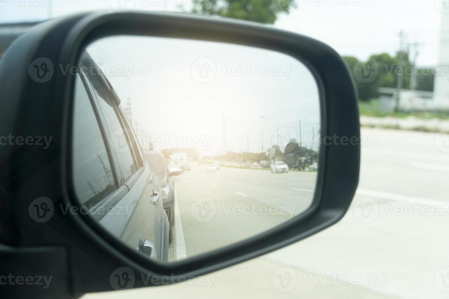 Abstract and blurred view of traffic from behind through the mirrors wing of a gray car. with abstract of shining from behind. photo