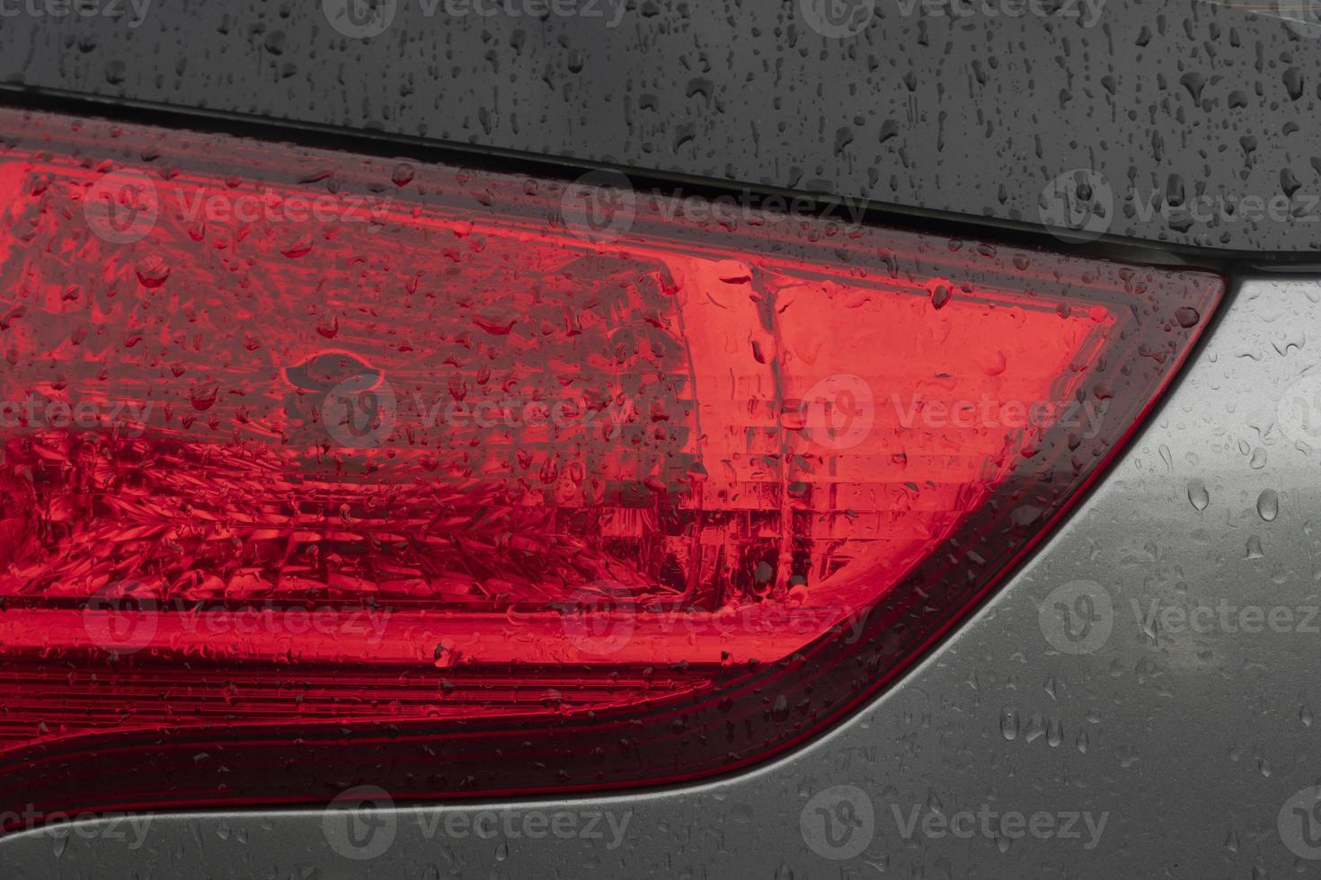 Close up tail light red color. Car gray color. On the boy with drop of rain. photo