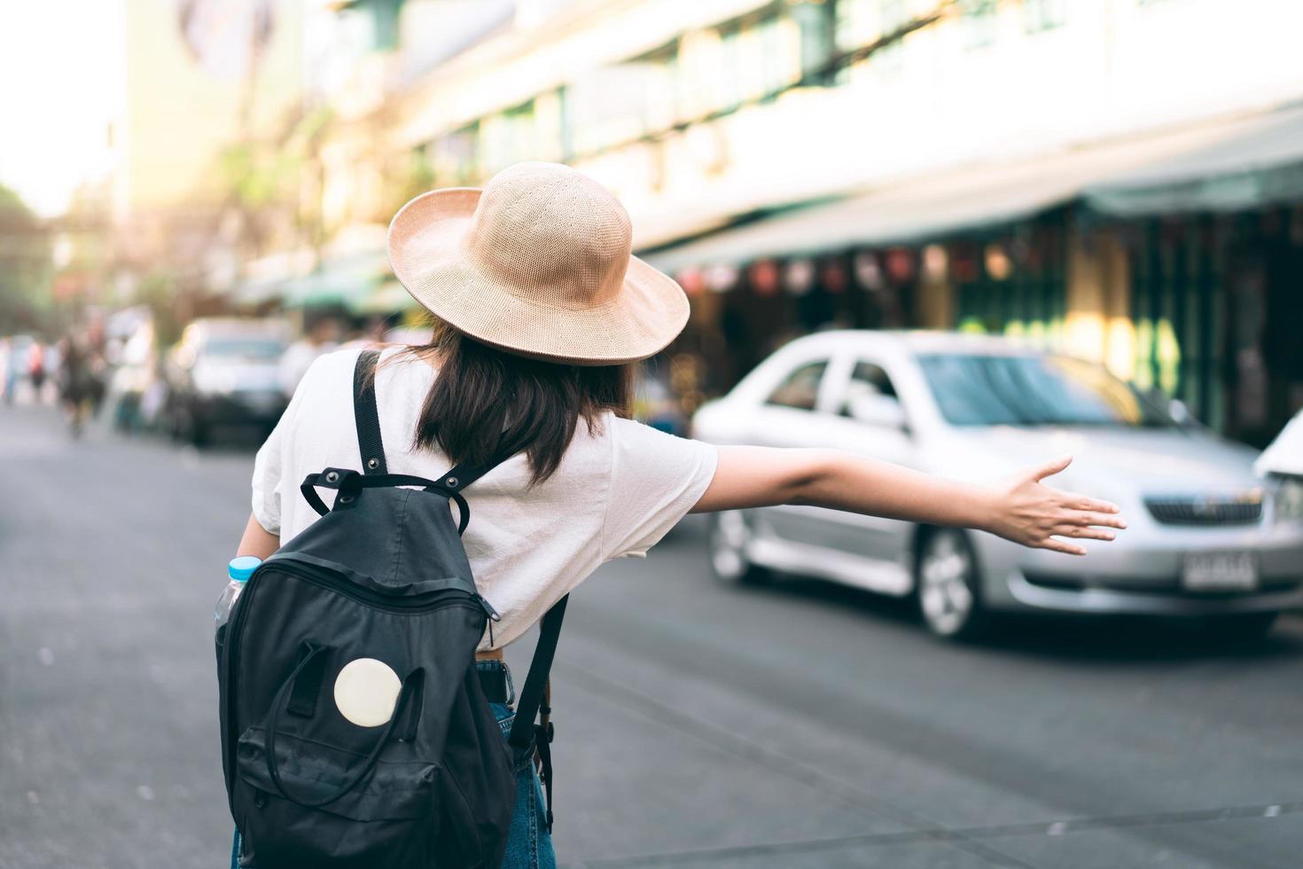 Back view of young asian traveller woman call a taxi for travel. photo