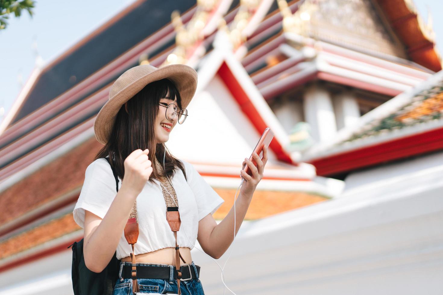 joven asiática viajera enérgica escucha música en streaming con un teléfono inteligente. foto