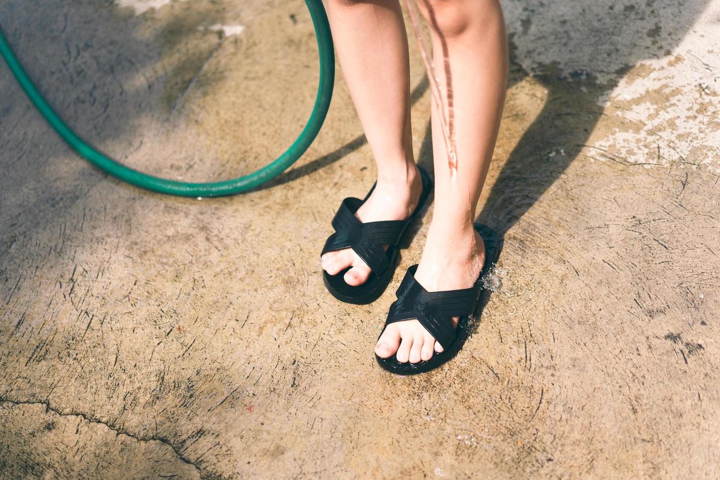 Asian teenager girl  wash a leg by water rubber strap. photo