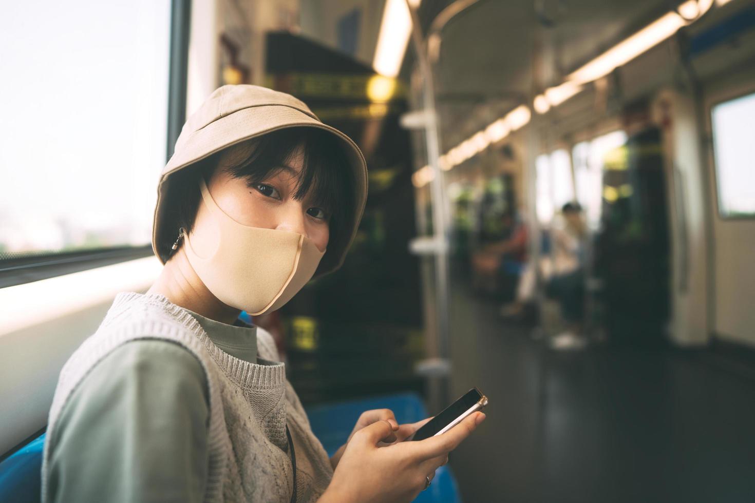 mujer asiática adulta joven con mascarilla para el transporte de salud pública en tren. foto