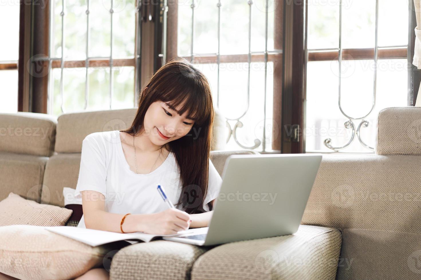 una adolescente asiática trabaja y estudia en línea a través de Internet en casa. foto