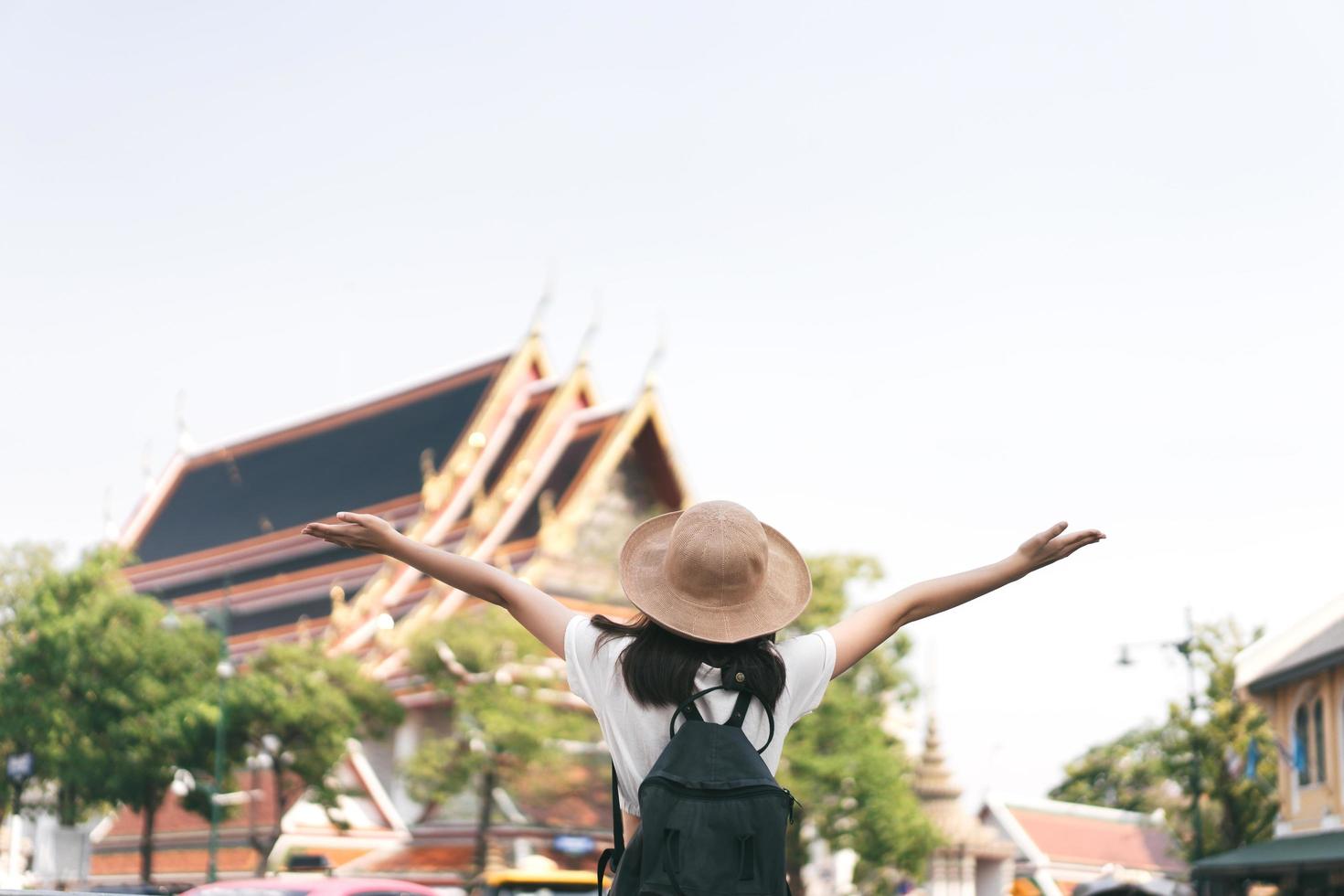 Rear view of young asian girl open arms to historical landmark. Bangkok, Thailand. photo
