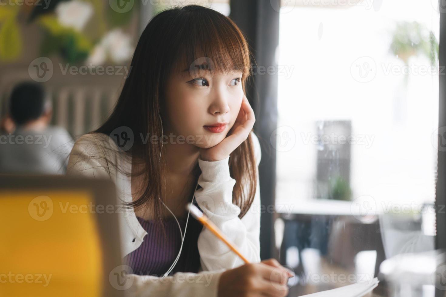 Young adult asian college student woman studying at cafe on day. photo