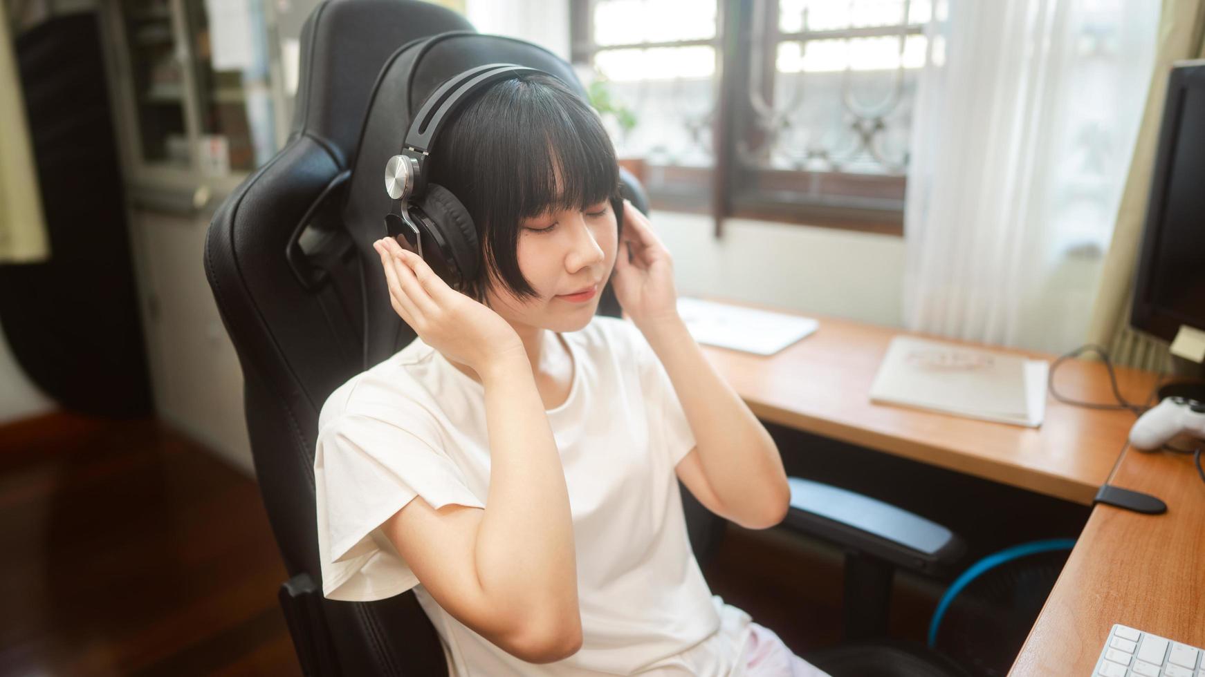 Young adult asian woman stay at home  wear headphone listening music online. photo