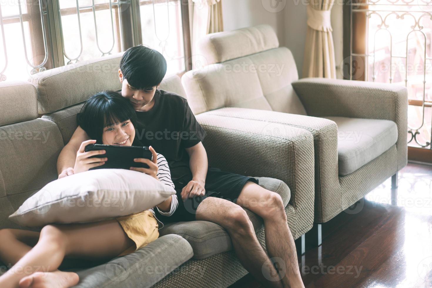 Young adult asian lover couple sitting on sofa and play game cozy style indoor on day. photo