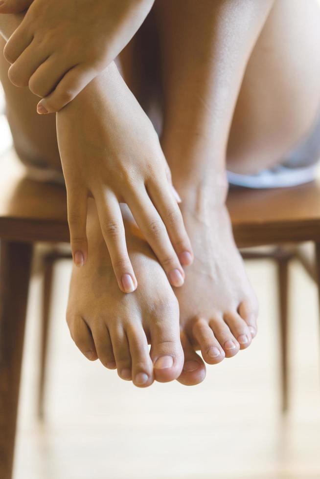 piel de la pierna de la mujer asiática con los pies descalzos y el toque de la mano. foto