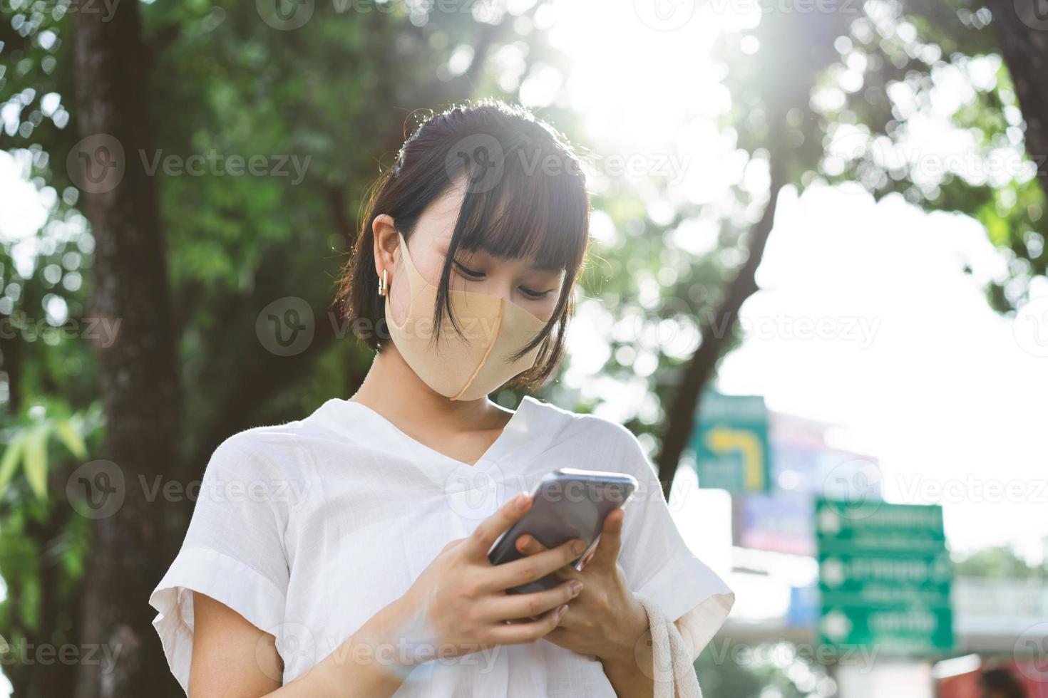 Young adult business asian working woman wear face mask using mobile phone application. photo