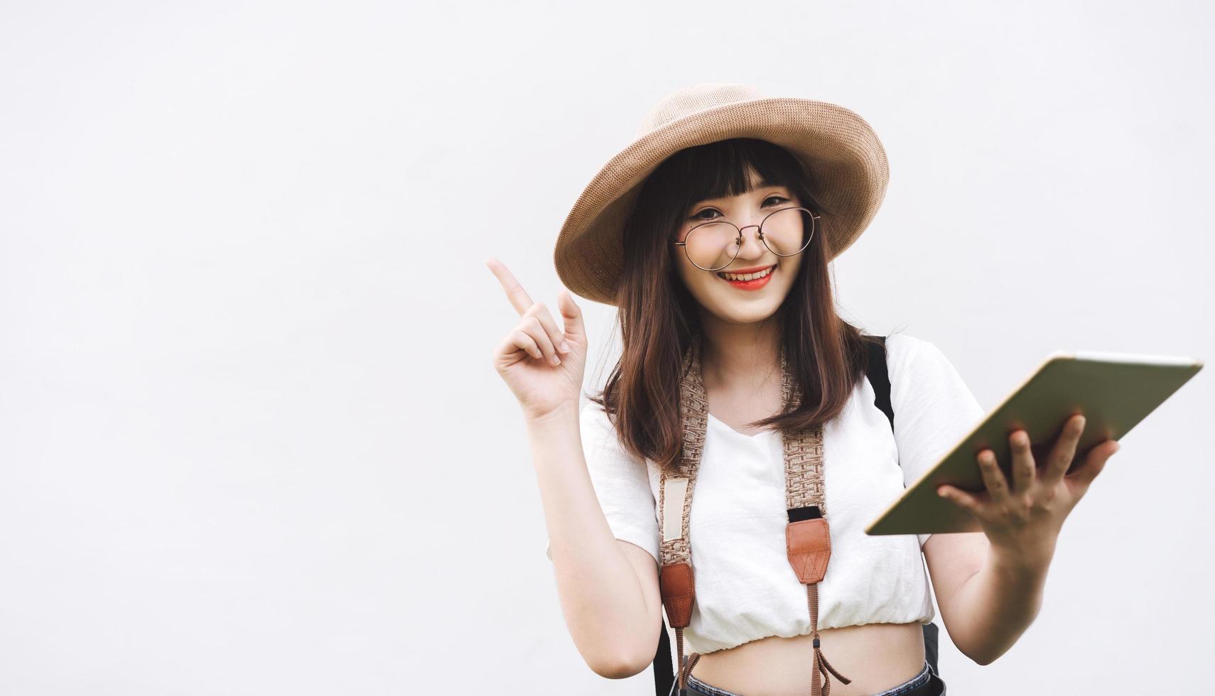 una joven asiática sonriente usa gafas sosteniendo una mesa para un viaje inteligente. foto
