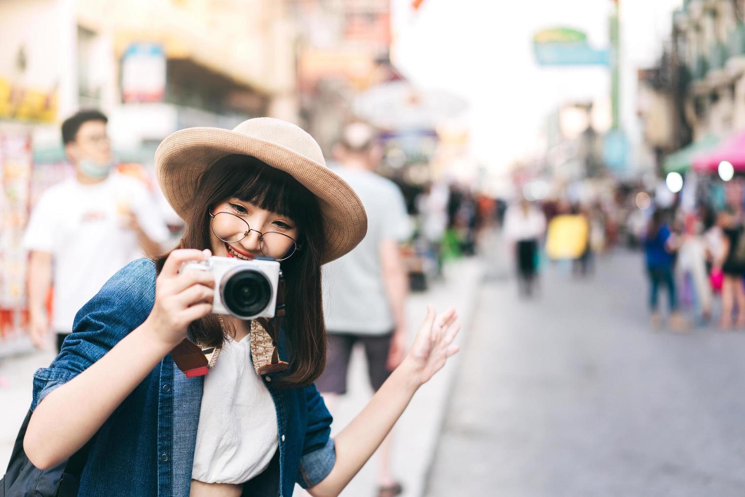 Young asian woman traveller take a photo by camera at khaosan street road.