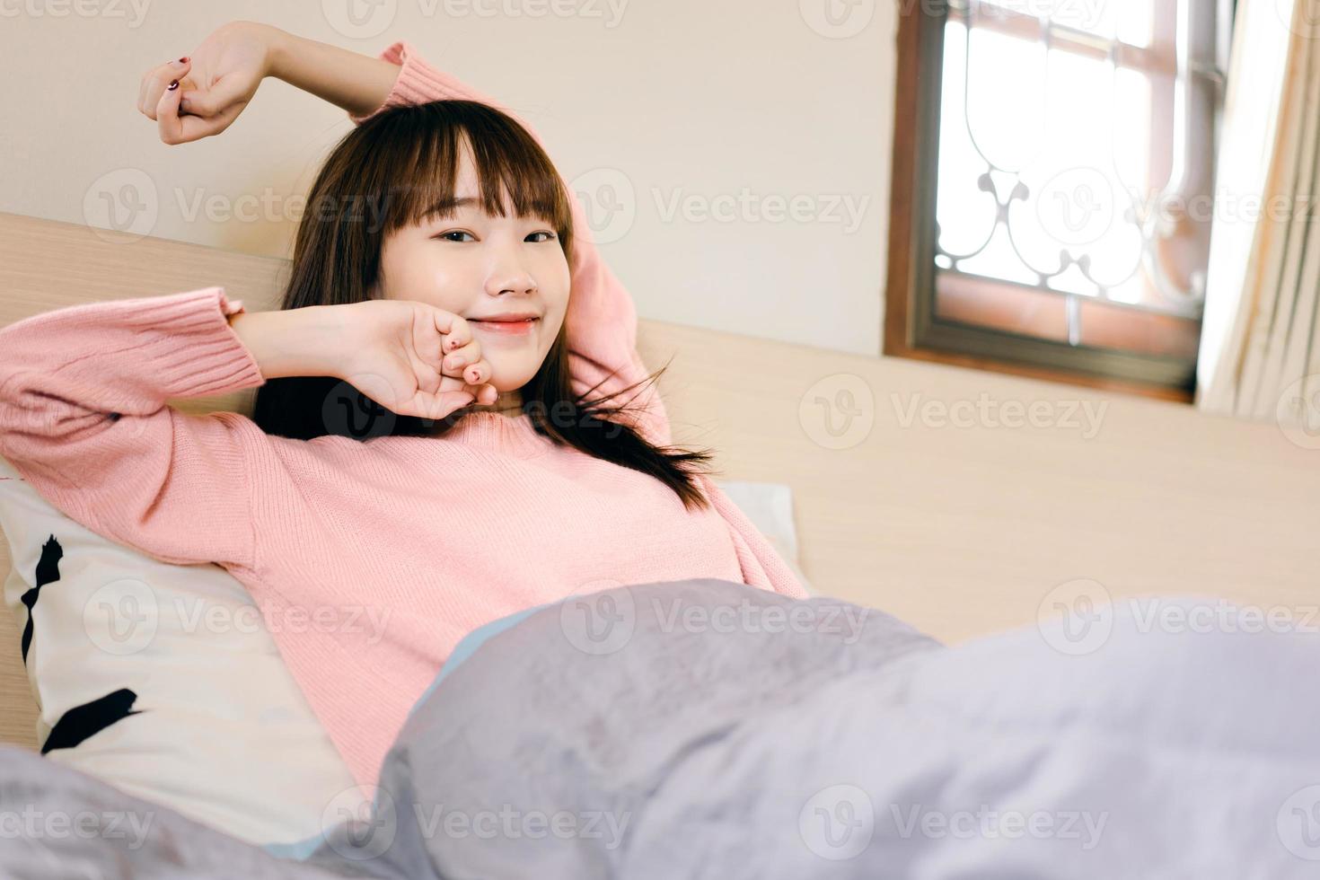 Wake up arm stretch asian teenager woman in bedroom. photo