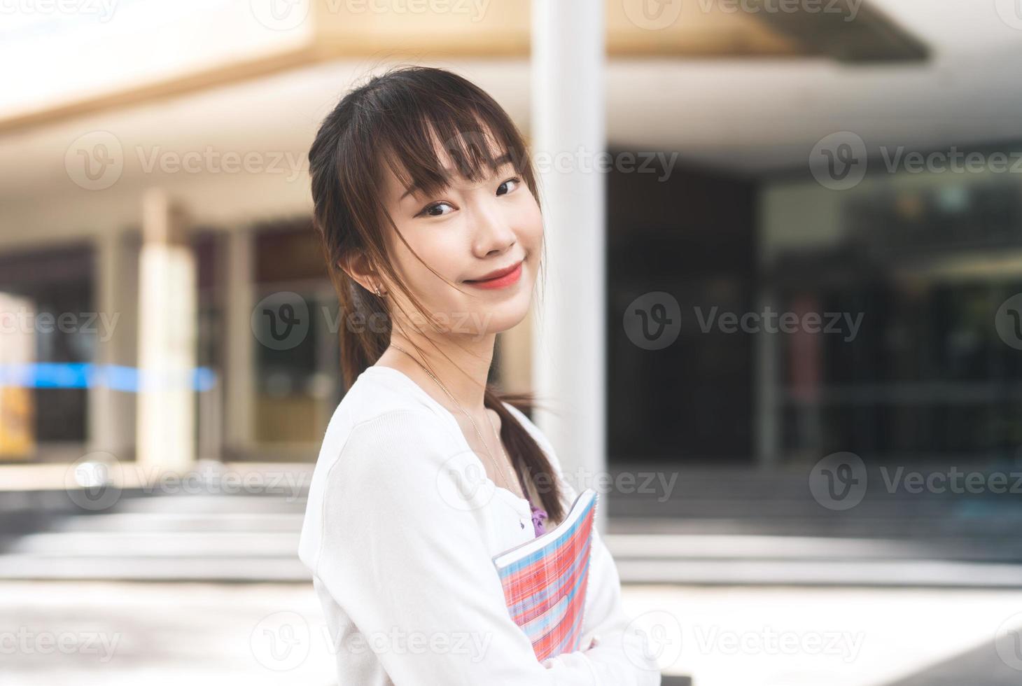 retrato de una joven estudiante universitaria asiática adulta con un cuaderno el día en la ciudad. foto