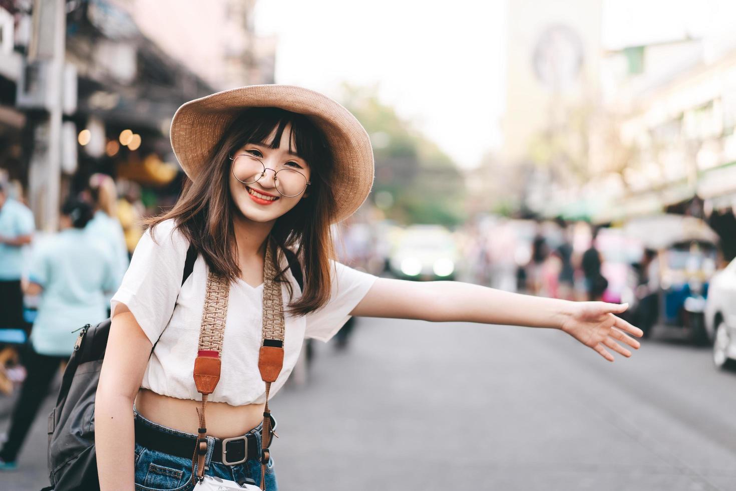 una joven viajera asiática llama a un taxi para hacer turismo en bangkok. foto